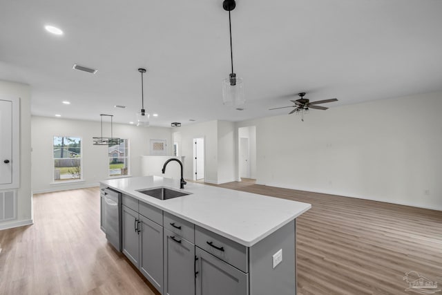 kitchen with light hardwood / wood-style flooring, sink, an island with sink, and decorative light fixtures