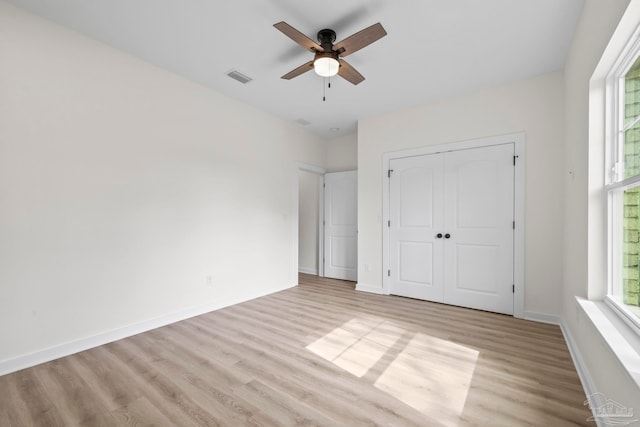 unfurnished bedroom with multiple windows, light wood-type flooring, and ceiling fan