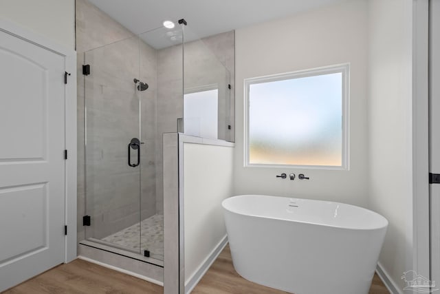 bathroom with independent shower and bath and wood-type flooring