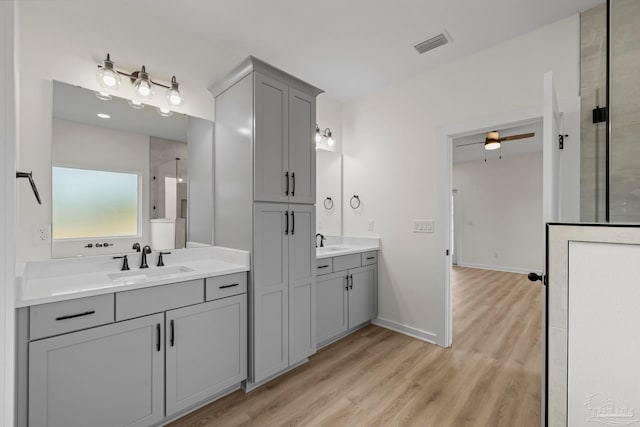 bathroom featuring walk in shower, vanity, hardwood / wood-style floors, and ceiling fan