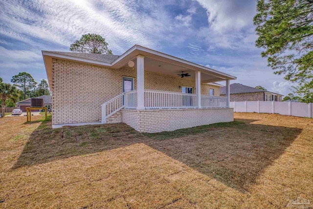 back of house with ceiling fan and a lawn