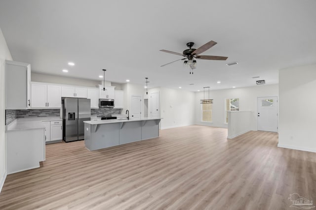 kitchen with white cabinets, a kitchen island, light hardwood / wood-style floors, decorative light fixtures, and stainless steel appliances