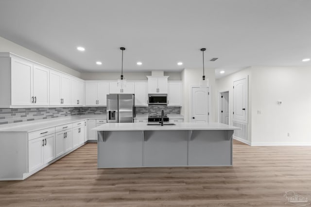 kitchen with white cabinetry, a kitchen island with sink, stainless steel appliances, and pendant lighting