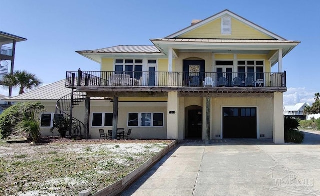 beach home with metal roof, an attached garage, stairs, driveway, and stucco siding