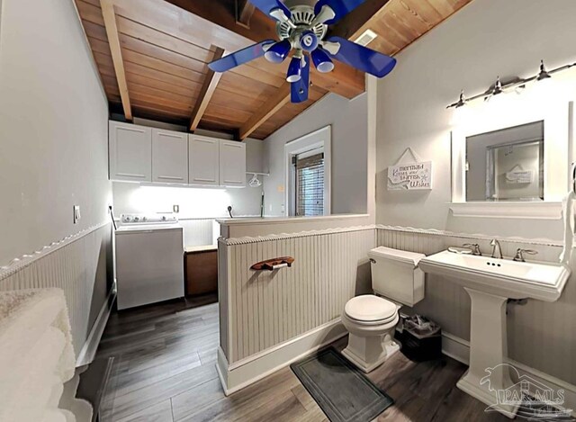 bathroom with a ceiling fan, lofted ceiling with beams, a wainscoted wall, wooden ceiling, and wood finished floors