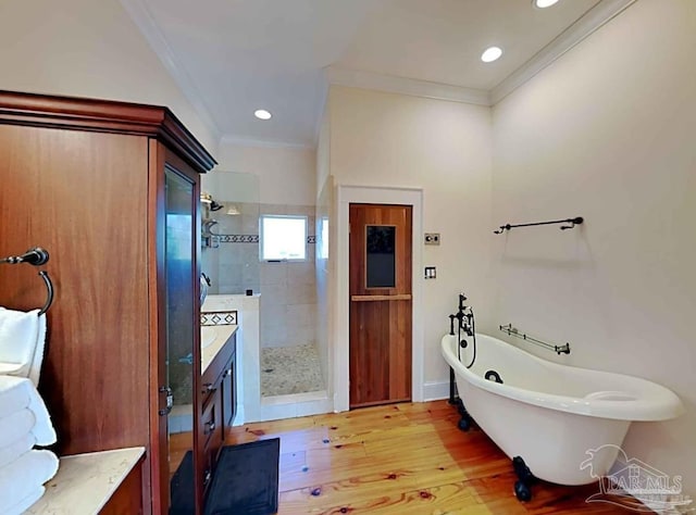 full bath featuring a freestanding tub, wood finished floors, vanity, ornamental molding, and a stall shower