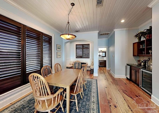 dining area featuring wine cooler, crown molding, visible vents, wood ceiling, and light wood-type flooring