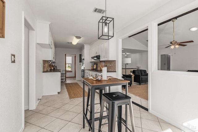 kitchen featuring white cabinetry, ceiling fan, light tile patterned floors, a kitchen breakfast bar, and pendant lighting