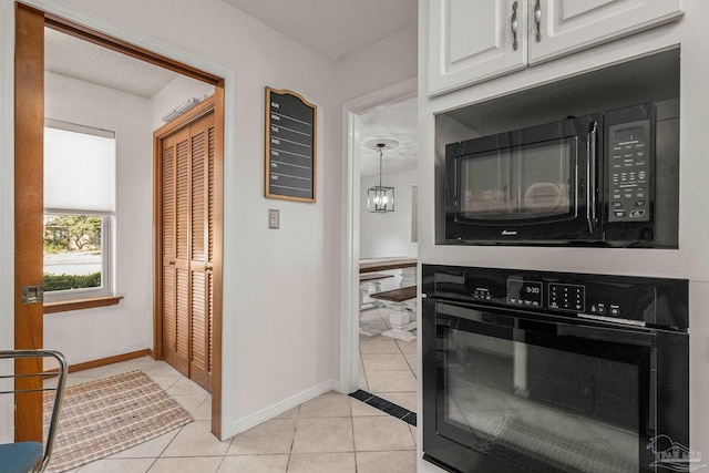 kitchen with white cabinetry, black appliances, and light tile patterned floors