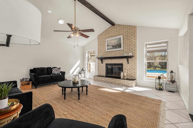 living room with a brick fireplace, ceiling fan, light tile patterned floors, and vaulted ceiling with beams