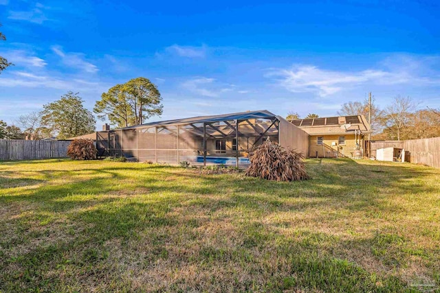 rear view of house featuring a yard, a fenced in pool, and glass enclosure