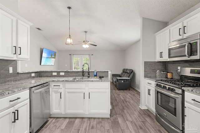 kitchen with stainless steel appliances, white cabinets, sink, and kitchen peninsula