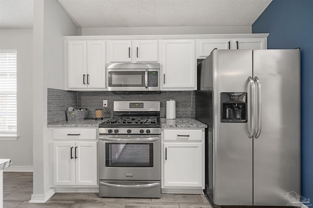 kitchen with white cabinets, appliances with stainless steel finishes, a textured ceiling, and light stone counters