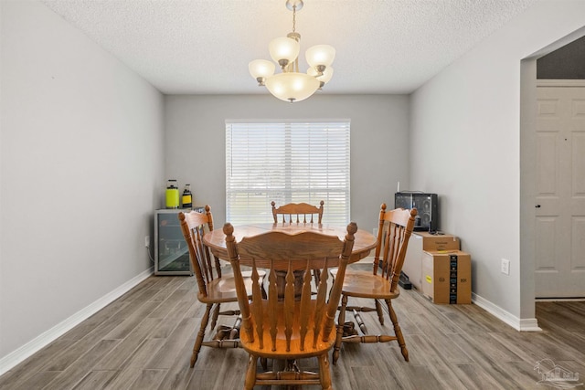 dining space with wood-type flooring, a textured ceiling, and a chandelier