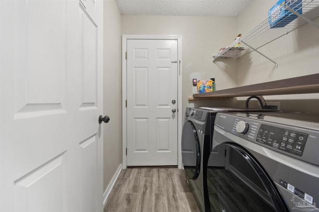 laundry room with separate washer and dryer, a textured ceiling, and light wood-type flooring