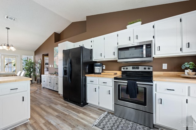 kitchen with decorative light fixtures, white cabinets, stainless steel appliances, and lofted ceiling