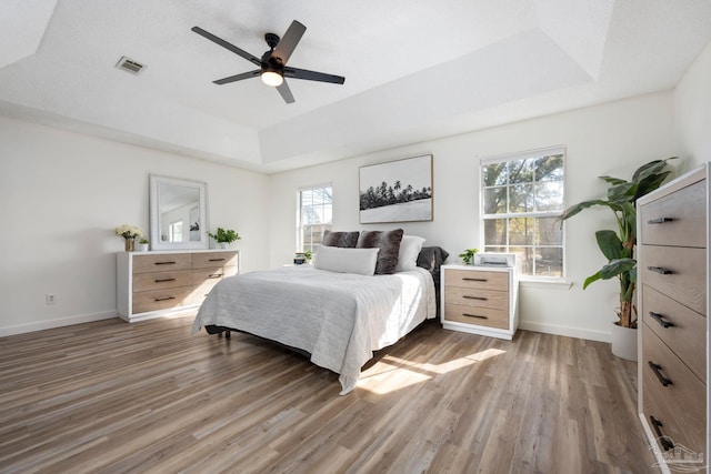 bedroom with ceiling fan, a raised ceiling, and dark hardwood / wood-style floors