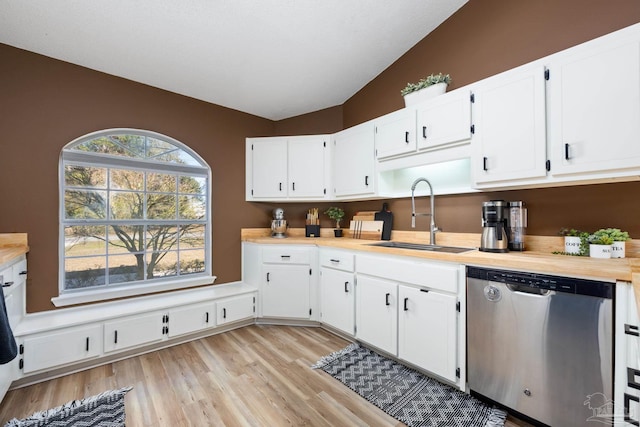 kitchen with sink, white cabinetry, stainless steel dishwasher, and lofted ceiling