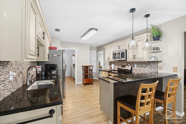 kitchen with kitchen peninsula, appliances with stainless steel finishes, a textured ceiling, and hanging light fixtures