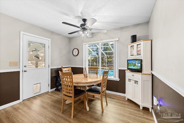 dining space with a textured ceiling, light wood-type flooring, and ceiling fan