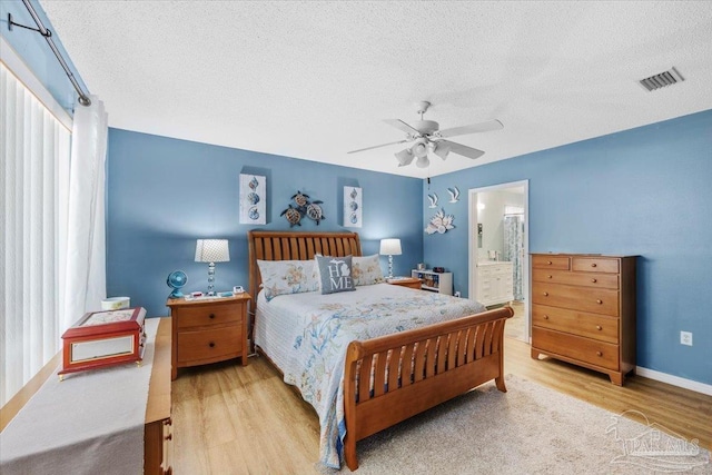 bedroom with a textured ceiling, light hardwood / wood-style flooring, ensuite bath, and ceiling fan