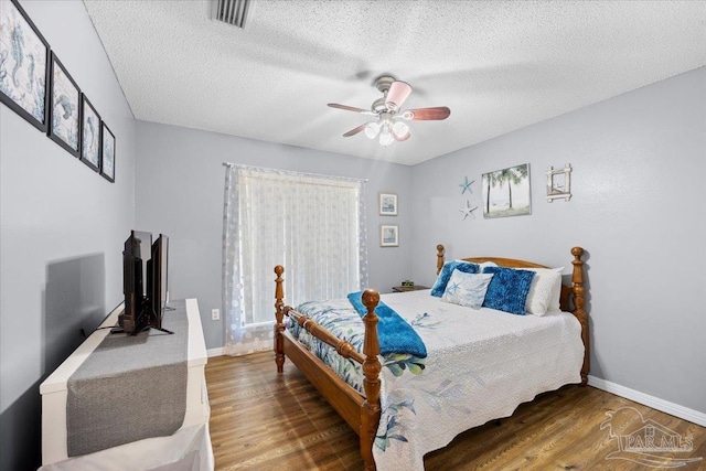 bedroom featuring ceiling fan, hardwood / wood-style floors, and a textured ceiling