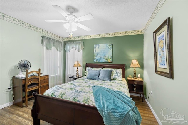 bedroom featuring ceiling fan, wood-type flooring, and a textured ceiling