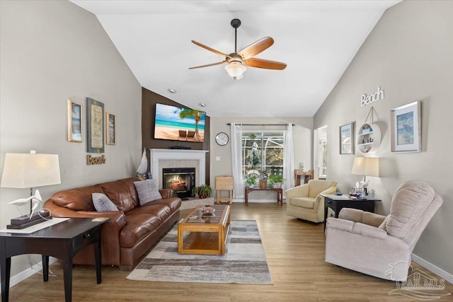 living room with a fireplace, wood-type flooring, ceiling fan, and lofted ceiling