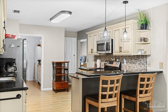 kitchen with tasteful backsplash, decorative light fixtures, a kitchen bar, kitchen peninsula, and stainless steel appliances