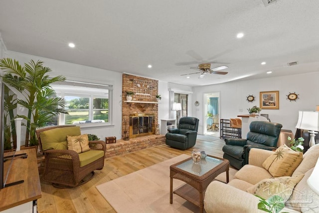 living room with a fireplace, light hardwood / wood-style floors, and ceiling fan