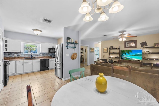 dining space featuring sink, light tile patterned flooring, and ceiling fan with notable chandelier