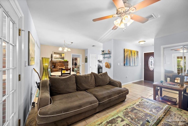 tiled living room featuring ceiling fan with notable chandelier