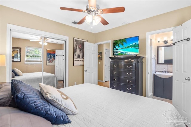 bedroom with ensuite bathroom, ceiling fan, sink, and a closet