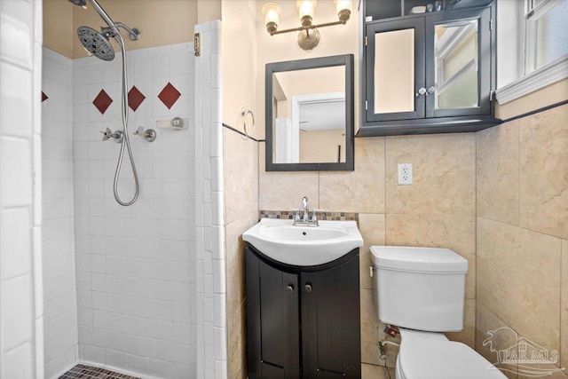 bathroom featuring tile walls, a tile shower, vanity, and toilet