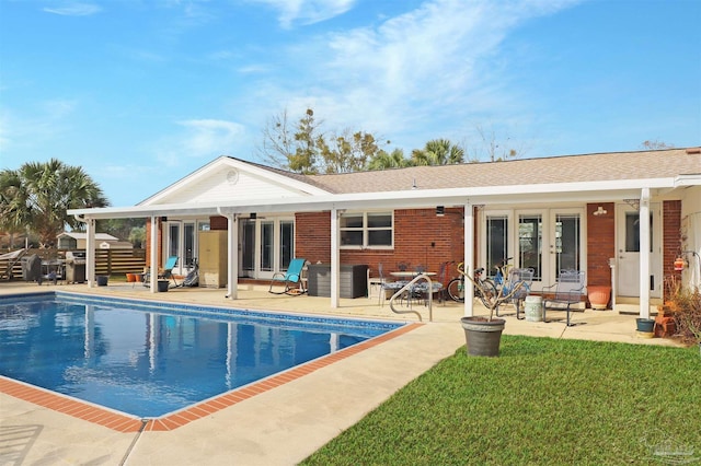 rear view of property featuring a fenced in pool, a lawn, a patio area, and french doors