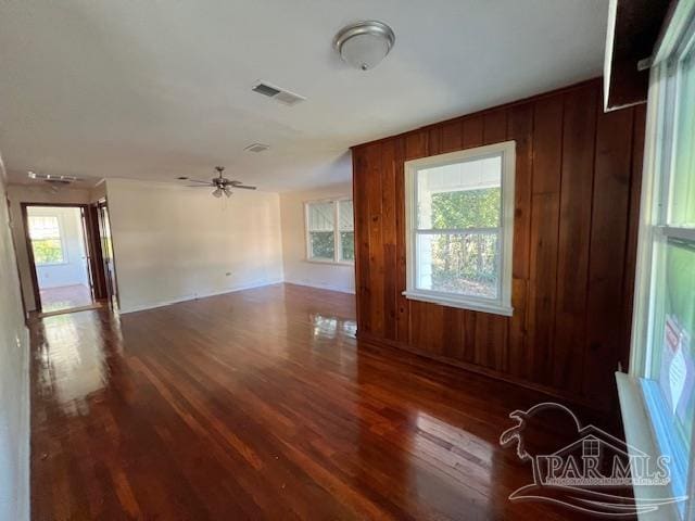 interior space featuring dark hardwood / wood-style flooring, wood walls, and ceiling fan