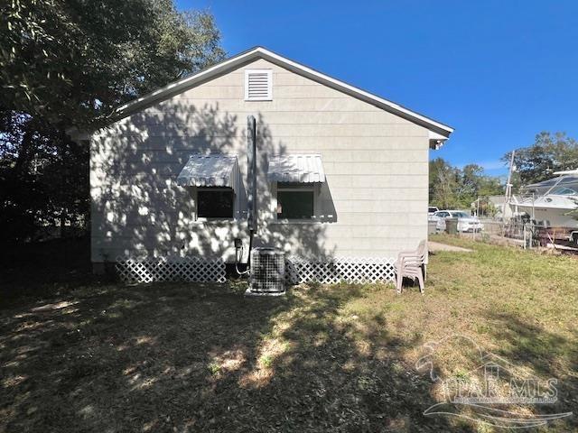 view of side of home featuring a yard and central AC unit