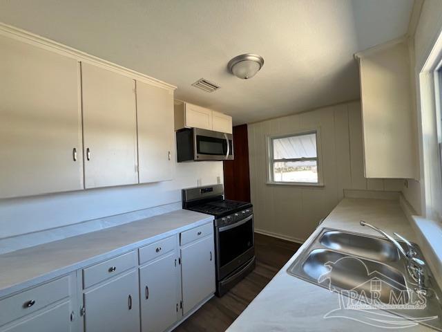 kitchen featuring appliances with stainless steel finishes, dark wood-type flooring, white cabinetry, and sink