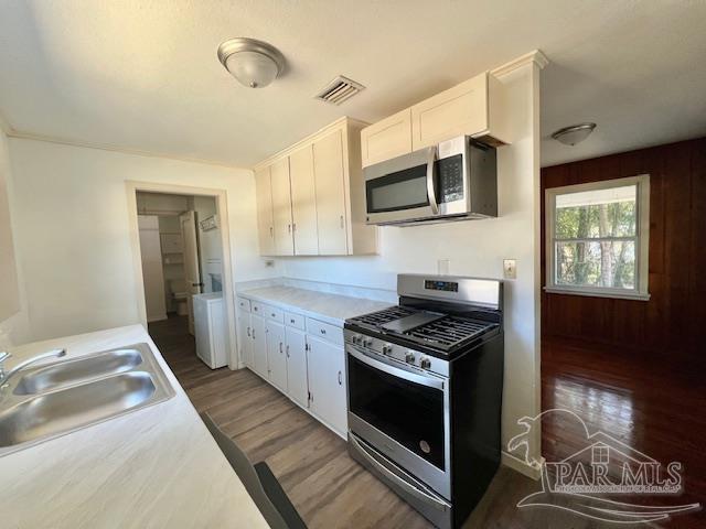 kitchen with stainless steel appliances, dark hardwood / wood-style flooring, white cabinets, and sink