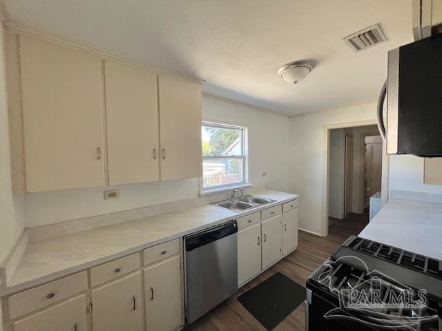 kitchen with appliances with stainless steel finishes, dark hardwood / wood-style flooring, white cabinets, and sink