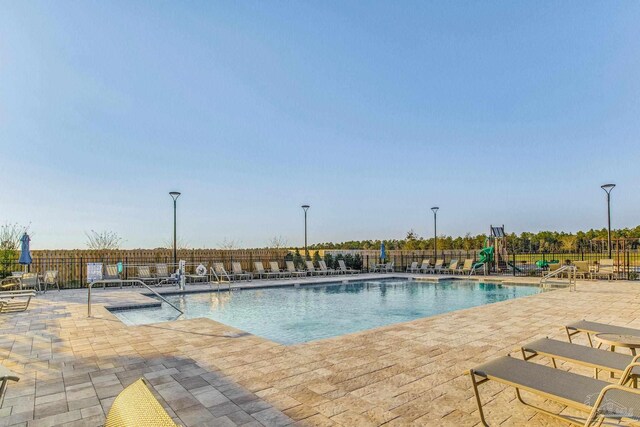 view of swimming pool with a patio area and a playground