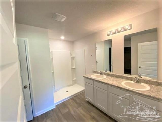 kitchen with a kitchen island with sink, hardwood / wood-style floors, white cabinets, sink, and appliances with stainless steel finishes