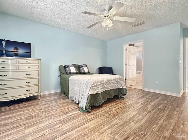 bedroom featuring ceiling fan, connected bathroom, light hardwood / wood-style floors, and a textured ceiling