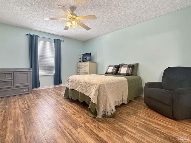 bedroom with ceiling fan, hardwood / wood-style floors, and a textured ceiling