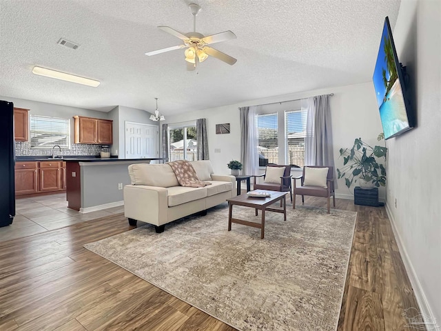 living room with hardwood / wood-style flooring, ceiling fan, sink, and a textured ceiling