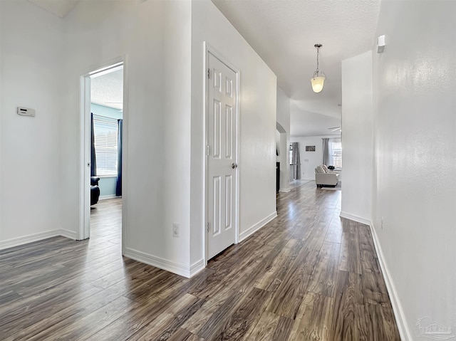 corridor featuring a textured ceiling and dark hardwood / wood-style flooring