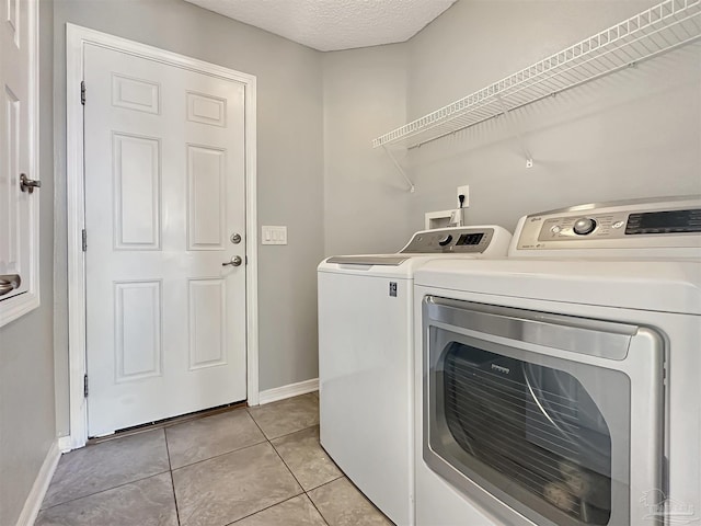 washroom featuring independent washer and dryer, a textured ceiling, and light tile patterned floors