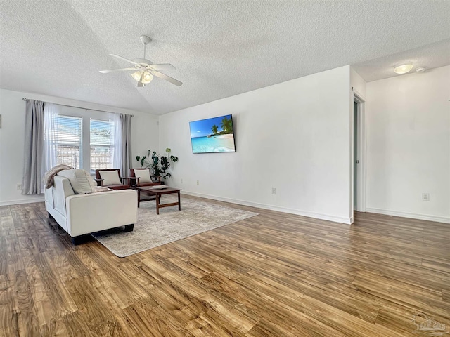 living room with hardwood / wood-style flooring, ceiling fan, and a textured ceiling