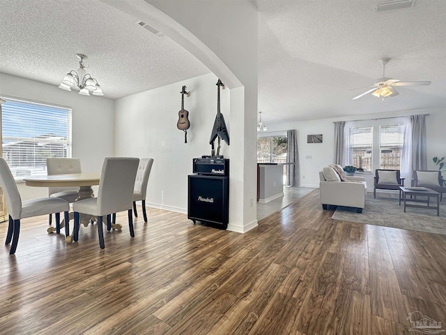 dining space with hardwood / wood-style floors, ceiling fan with notable chandelier, and a textured ceiling