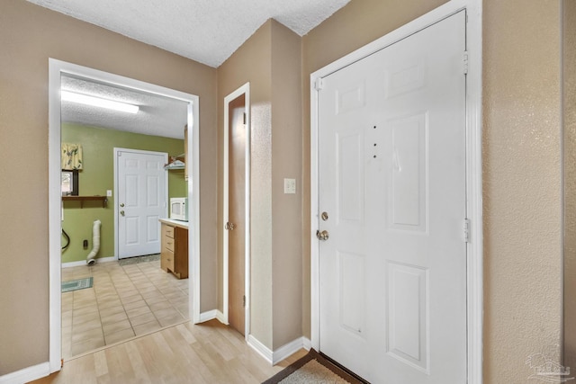 foyer entrance with light wood-type flooring and a textured ceiling